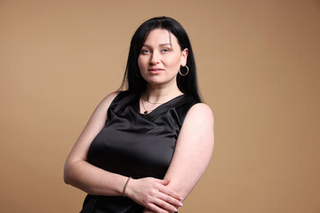 Naklejka premium Portrait of charming plus size model on beige background. Overweight