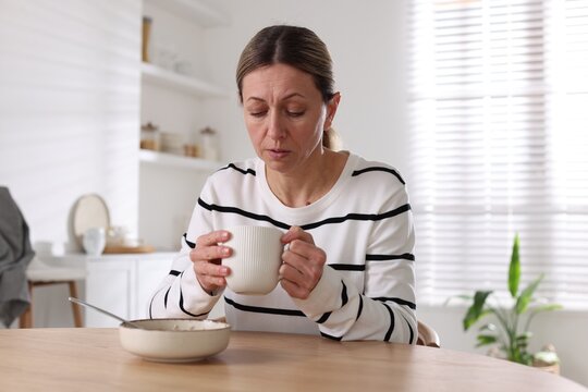 Depressed woman with appetite loss at table indoors