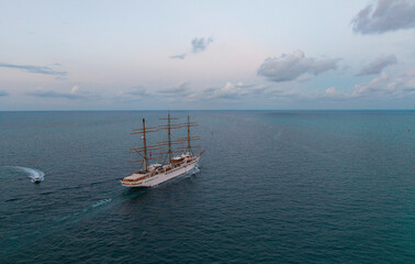 Obraz premium Sailing boat at dramatic sky seascape. Ship sailing the sea. Sail oat at port Miami. Travel by sea. Seascape horizon at sunset. Sea vacation. Sailboat vessel. Travel destination. Sail training ship