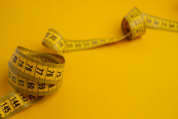 Yellow measuring tape on a yellow background. Tool for measuring length and volume. Tape for...