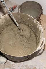 Fototapeta premium Construction worker mixing cement in bucket using mixing paddle attached to electric drill