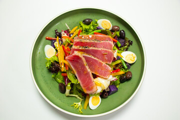 traditional tuna salad with potato, olives, beans, eggs and lettuce with white background