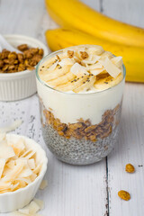 Chia pudding on coconut milk in a glass with banana on a light wooden background. Healthy breakfast, healthy lifestyle.