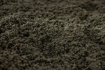 Detailed view of a rugged surface composed of small, dark granules with uniform size and color,...