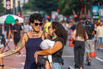 Lesbian couple talking while holding baby on closed street in São Paulo