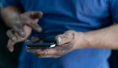 mechanic's hands using a cell phone