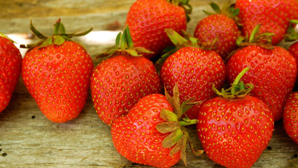 Juicy ripe strawberries on a wooden table in the rays of the sun. Strawberry harvesting. Growing organic strawberries. Sweet vitamin dessert.