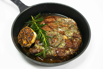 grilled beef steak with herb butter in an iron pan with white background