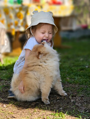 A playful child joyfully embracing a fluffy dog in the beautiful nature outdoors