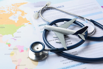 Medical tourism. Travel insurance application form, stethoscope and airplane model on world map,...