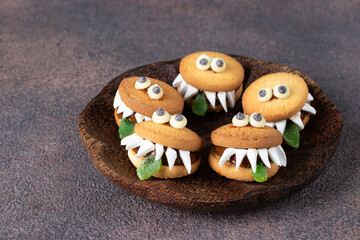 Halloween Party Treats - Cookie Monsters with Marshmallows, Condensed milk and Chocolate on wooden plate
