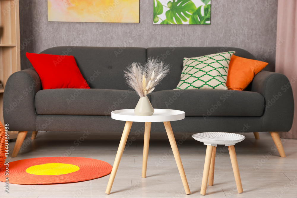 Poster stylish nesting tables near sofa at home