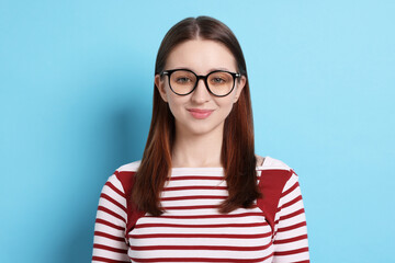 Teenage girl in glasses on light blue background