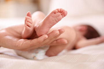 Mother with her little baby on bed indoors, closeup