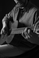 Obraz premium Man playing guitar on dark background, focus on hand. Black and white effect