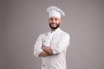 Portrait of confectioner in uniform with crossed arms on light grey background