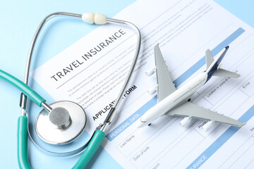 Medical tourism. Travel insurance application form, stethoscope and plane model on light blue background, closeup