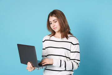 Portrait of teenage girl using laptop on light blue background