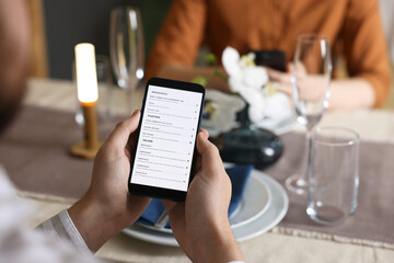 Couple choosing dishes from digital menu at restaurant, closeup