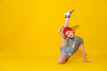 Girl in stylish clothes dancing on yellow background, space for text
