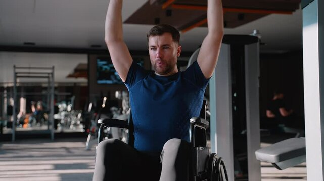 Man in wheelchair exercising deltoid muscle at gym