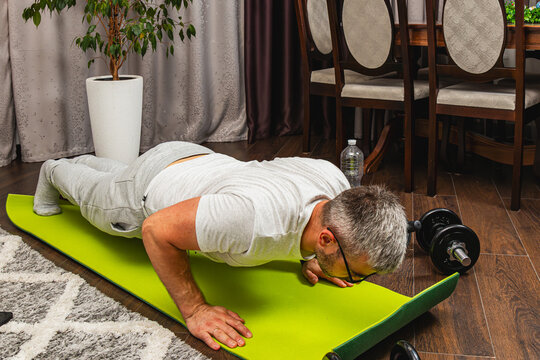 Man exercising with push-ups on a green yoga mat indoors
