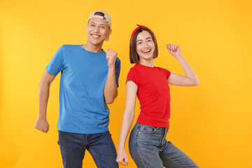 Obraz premium Happy couple in stylish clothes dancing on yellow background