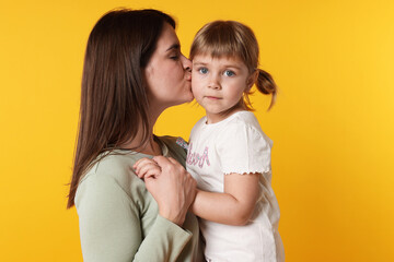 Happy mother and her cute daughter on orange background
