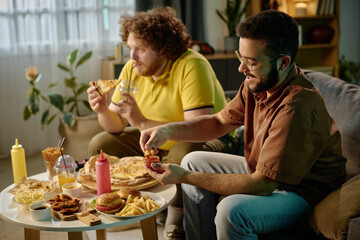 Friends sharing takeout food while sitting at a table and laughing, with various dishes including...