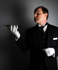 Butler or Formal Waiter in Black Morning Coat and White Gloves Holding Serving Tray. Professional Hospitality and Courtesy.
