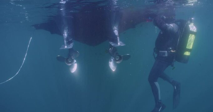  Scuba diver cleaning transom of boat open ocean.