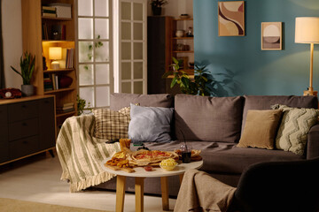 Cozy living room featuring comfortable couch and snack table with snacks and drinks. Shelves and...