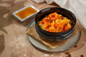 Rustic Millet Porridge with Pumpkin and Raisins in a Black Bowl
