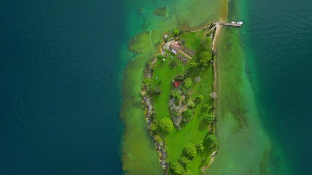 Aerial view of Isola Dei Conigli in Manerba with the cliff overlooking Lake Garda with crystal clear water. We are in the province of Brescia, Lombardy, Italy. The video expresses serenity and peace