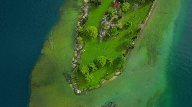 Aerial view of Isola Dei Conigli in Manerba with the cliff overlooking Lake Garda with crystal clear water. We are in the province of Brescia, Lombardy, Italy. The video expresses serenity and peace