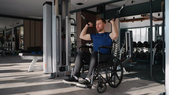 Man in wheelchair using lat pulldown machine in gym