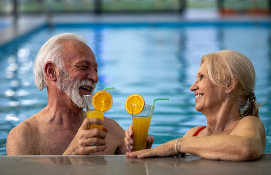Senior couple relaxing in pool talking and drinking