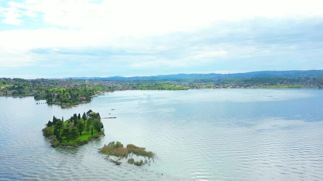 Aerial view of Isola Dei Conigli in Manerba with the cliff overlooking Lake Garda with crystal clear water. We are in the province of Brescia, Lombardy, Italy. The video expresses serenity and peace