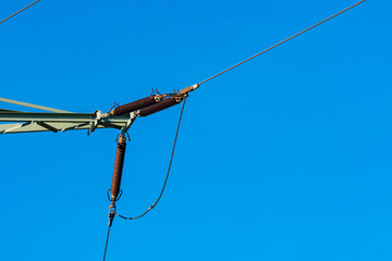 Power lines with insulators under clear blue sky.
