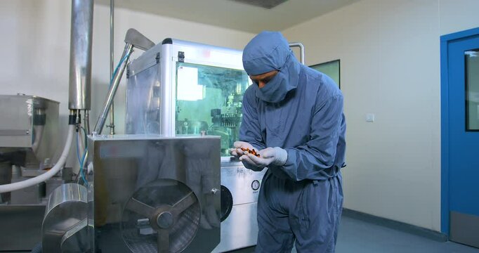 worker using automatic capsule making machine. Pharmaceutical Capsule pills tablets being manufactured by a machine. automatic medicine tablet making machine. Production line at pharmaceutical factory