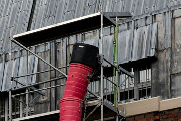 Construction scaffolding with red construction debris pipe at worksite