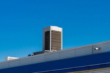 Fototapeta premium Cooling unit on building rooftop under clear blue sky