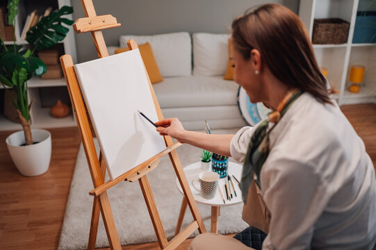Female artist starting new painting on canvas at home studio