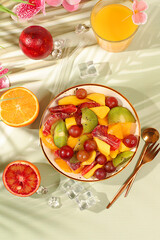 Healthy breakfast with ingredients, kitchen background. Fruit salad with kiwi, mango, grapes, nuts, citrus fruits with chia seeds for weight loss and a glass of orange juice. Natural nutrition
