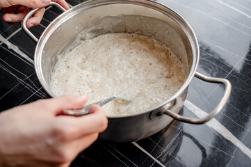 Homemade Pizza Preparation with Three Cheeses – Female Hands in Action. A warm, close-up scene of a woman’s hands preparing homemade pizza dough on a kitchen countertop. Photo recipe.