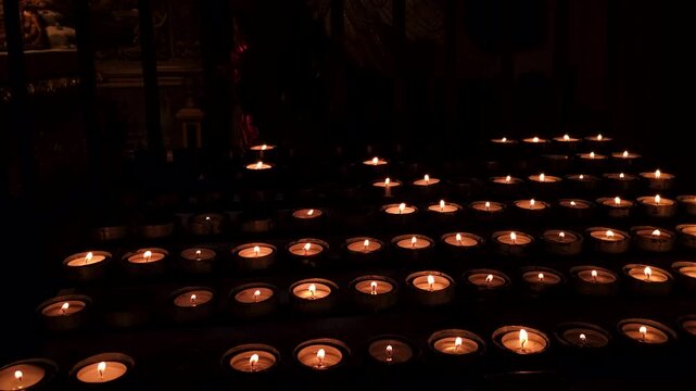 Banks of flickering prayer candles in a dark cathedral
