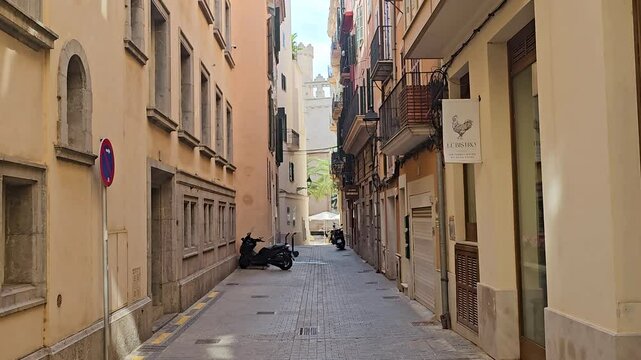 Scooters parked on narrow Carrer de la Mar street between buildings-Palma, Mallorca