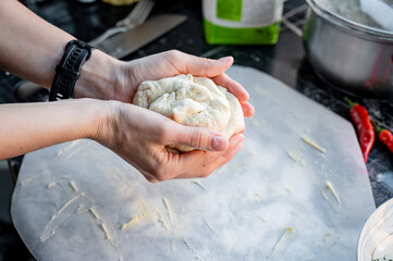 Homemade Pizza Preparation with Three Cheeses – Female Hands in Action. A warm, close-up scene of a woman’s hands preparing homemade pizza dough on a kitchen countertop. Photo recipe.
