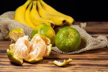 Oranges and Bananas, oranges and bananas positioned on a rustic wooden surface and dark background, selective focus.