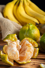 Oranges and Bananas, oranges and bananas positioned on a rustic wooden surface and dark background, selective focus.